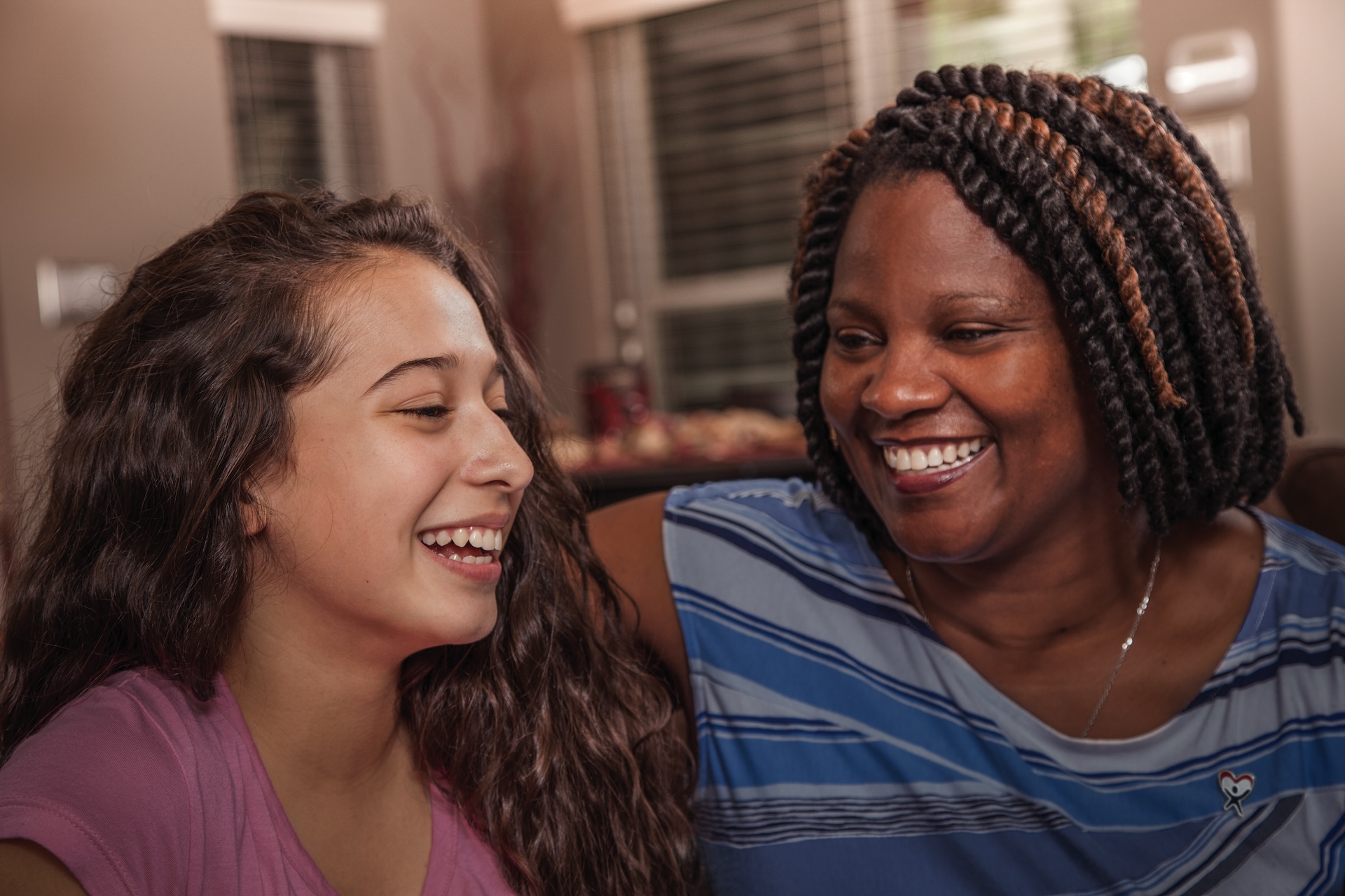 Multi-ethnic family. Teenage girls and mom at home. Hugs.